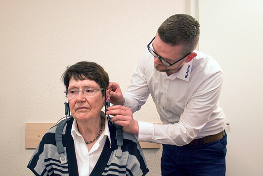 Hörtest bei älterer Frau durch Hörakustiker mit modernen Hörtestgeräten im Fachgeschäft.